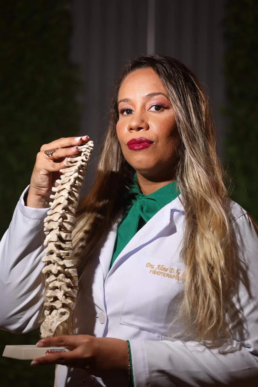 Dra. Aline Gonzaga com um modelo anatômico de coluna vertebral